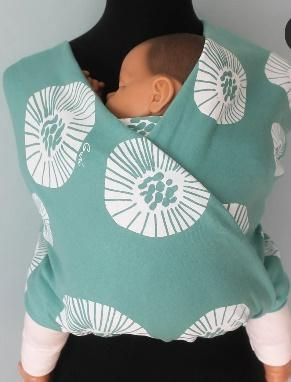 Bebé envuelto en un portabebés de color verde azulado con estampado de flores blancas