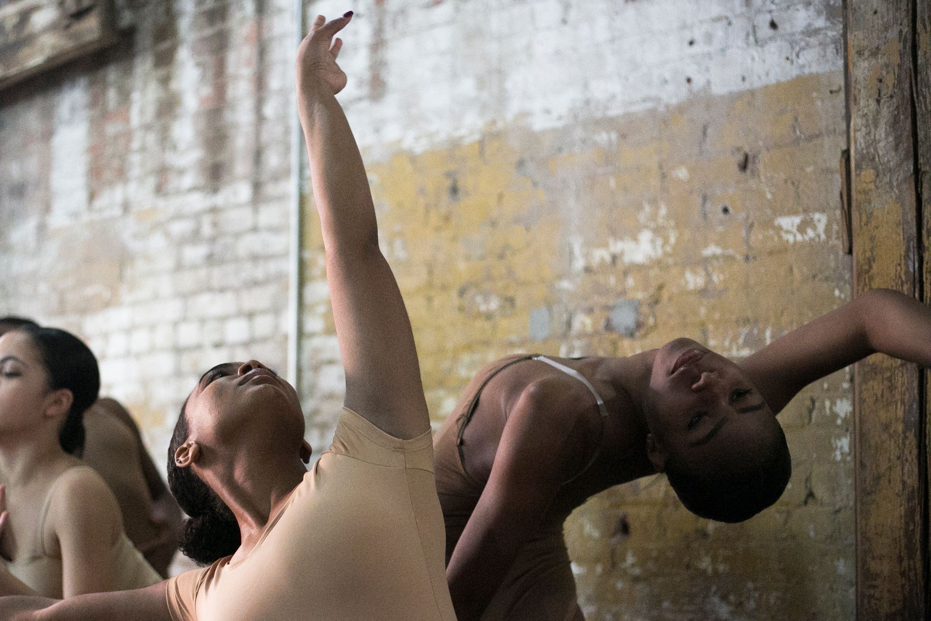 Dancers in beige attire practice ballet. 