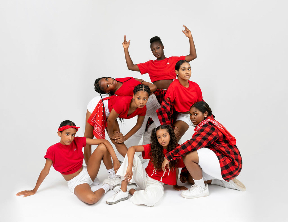 A group of dancers in red and white outfits, posing in a studio.