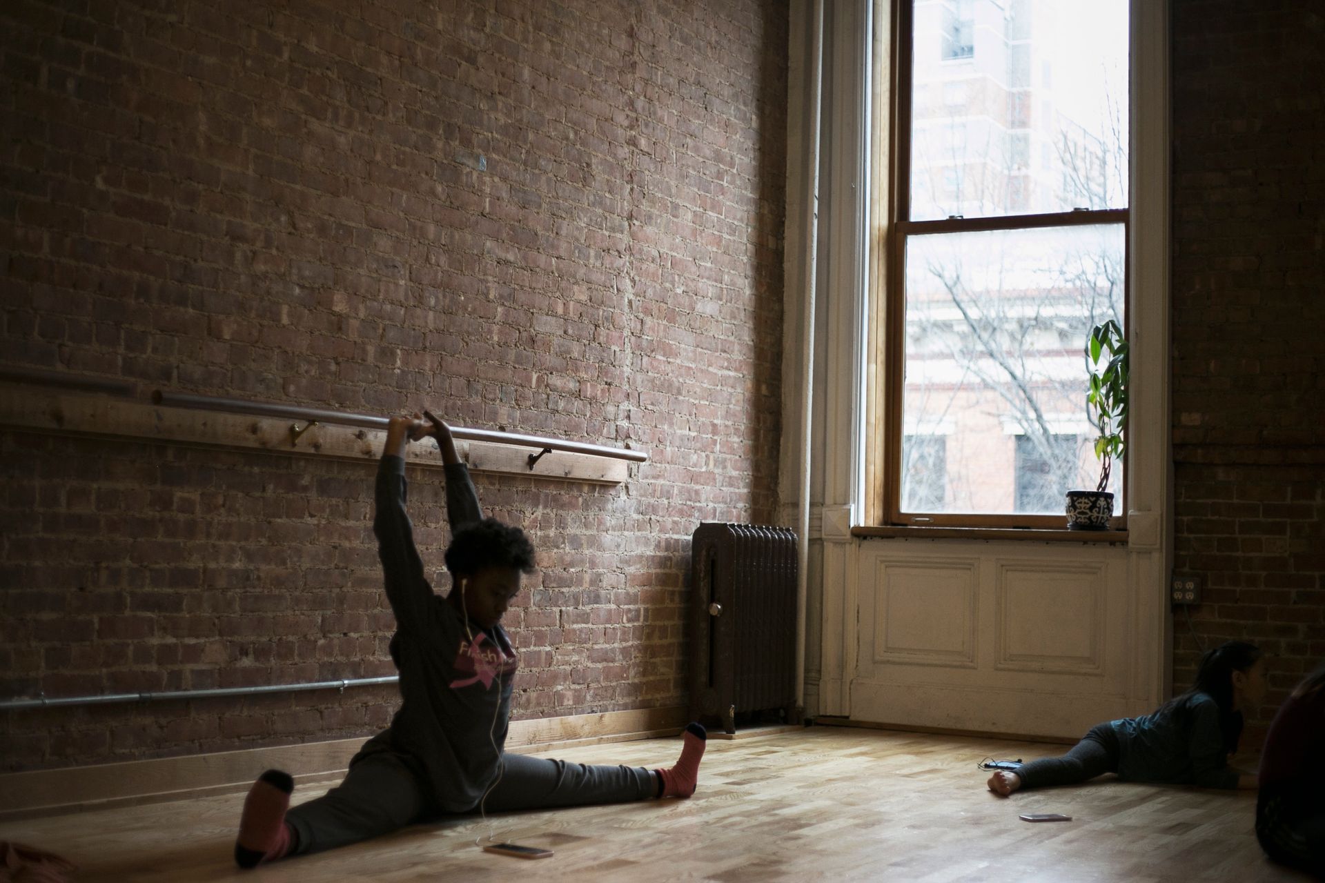 A dancer in a split stretches toward the ceiling in a room with a barre.