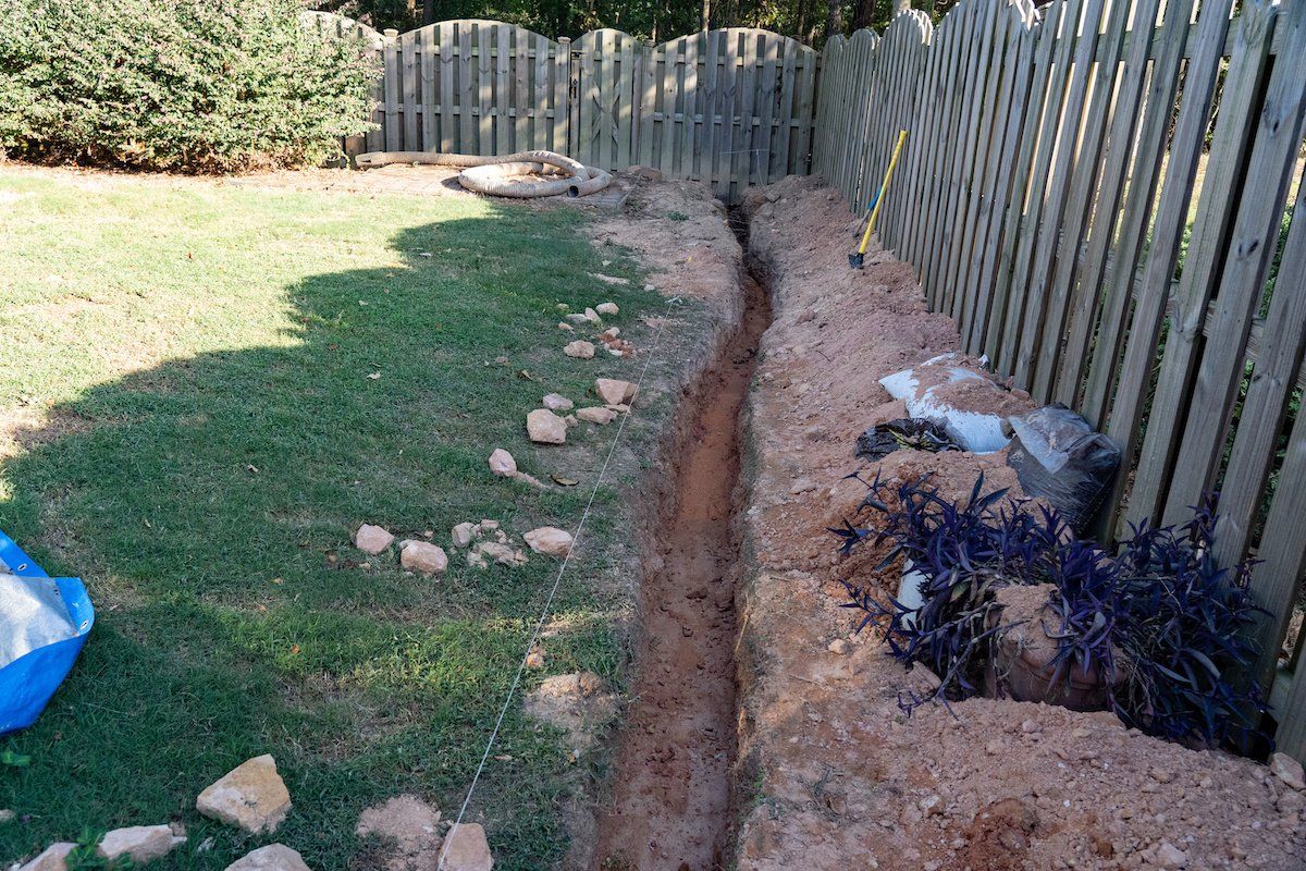 A trench being excavated as the initial phase of a French drain home improvement endeavor aimed at resolving drainage problems.