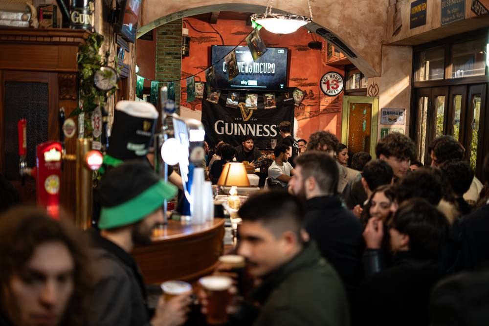 Pub irlandese affollato di gente, spine di birra, striscioni della Guinness e luci soffuse.