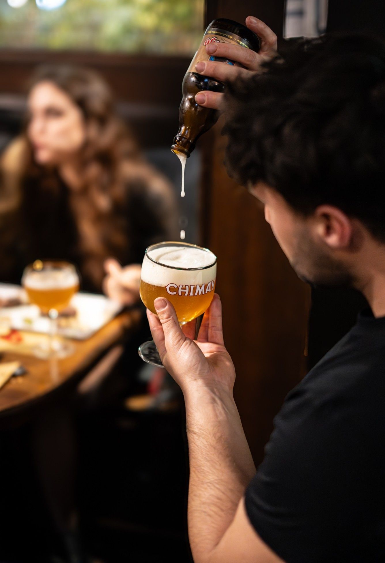 Una persona versa la birra in un bicchiere in un ristorante scarsamente illuminato.