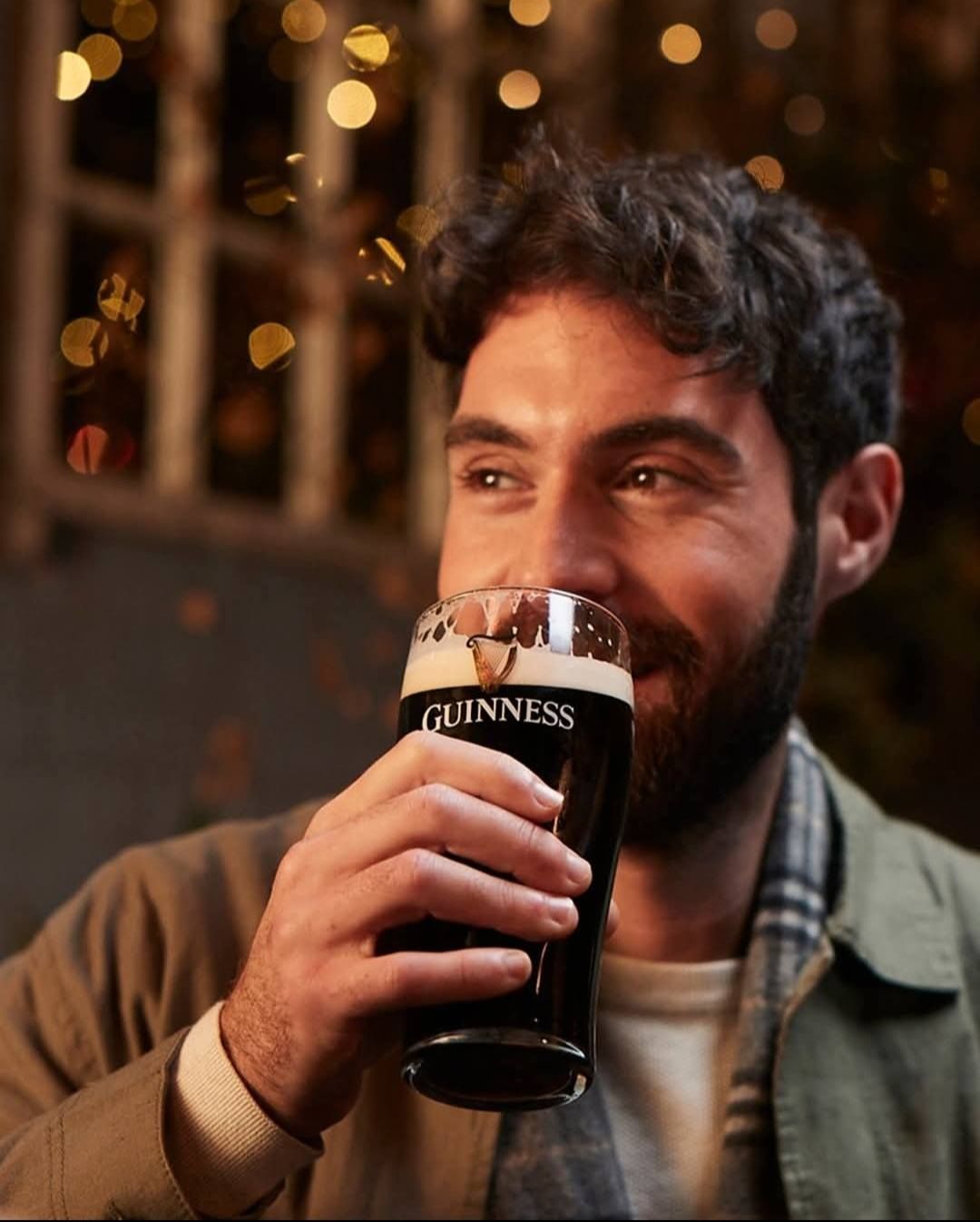 Uomo sorridente che beve Guinness in un pub, birra scura, in bianco e nero.