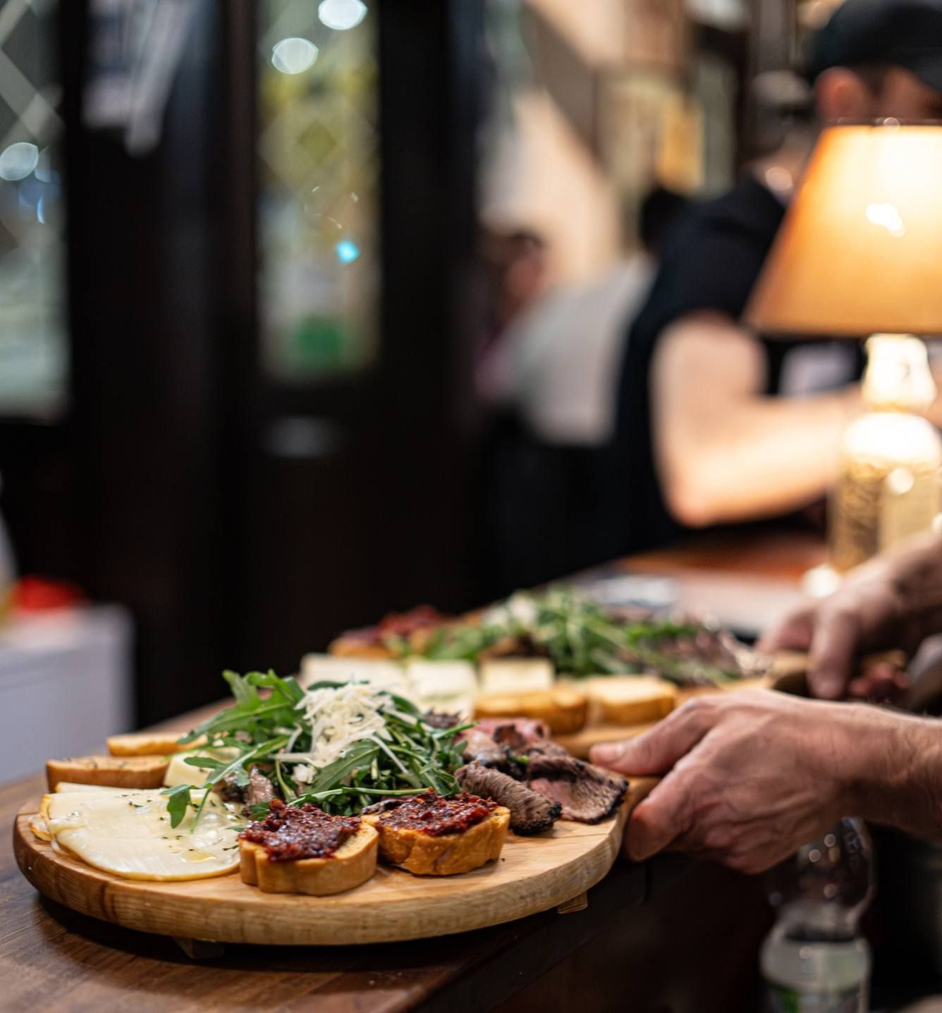 Tagliere di legno con formaggio, salumi e pane servito al bar.