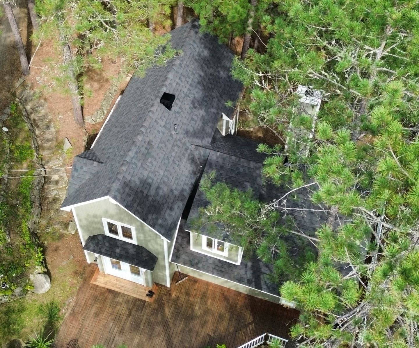 Vue aérienne d'une serre à deux étages avec un toit noir, entourée d'arbres.