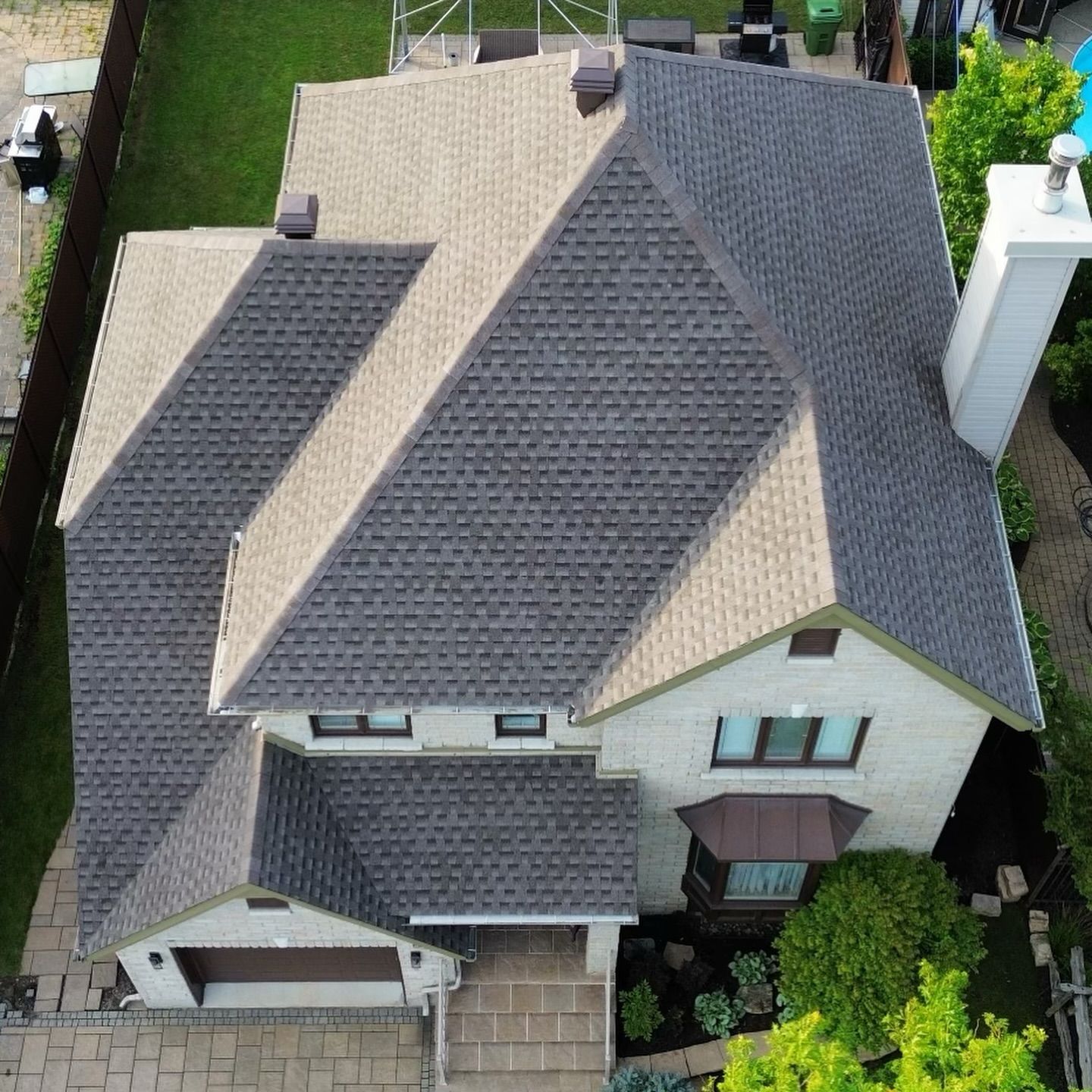 Vue aérienne d'une maison à deux étages avec un toit à angles multiples, des cheminées et un extérieur en briques.