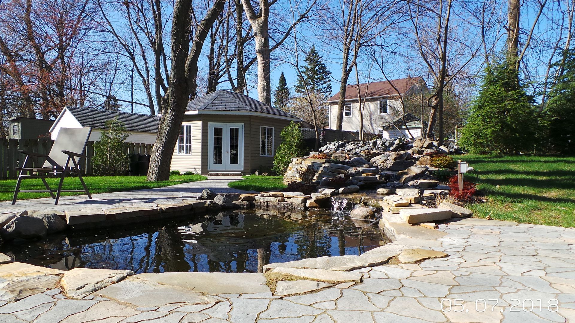 Un étang dans une cour arrière avec une maison en arrière-plan