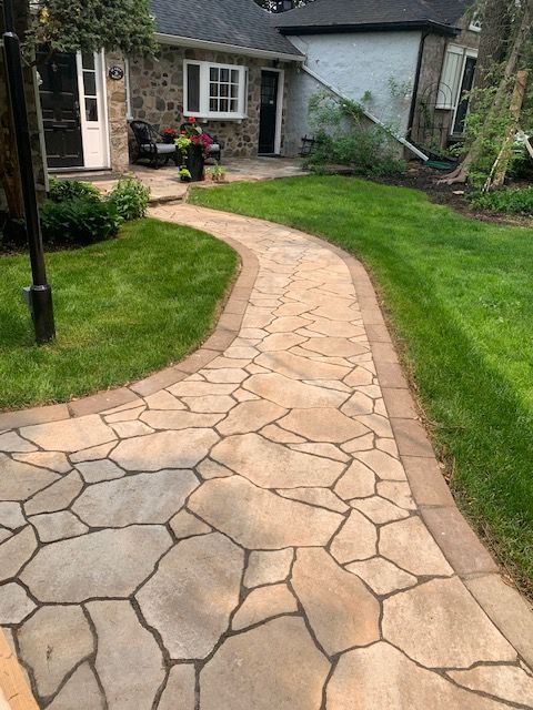 Une allée en pierre menant à une maison avec une pelouse verte luxuriante.