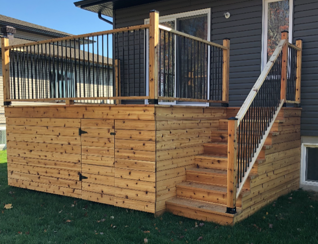 Une terrasse en bois avec des escaliers qui y mènent se trouve devant une maison.