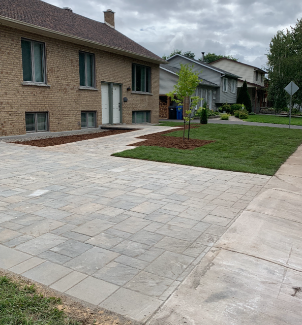 Une maison en brique avec une allée en béton devant elle