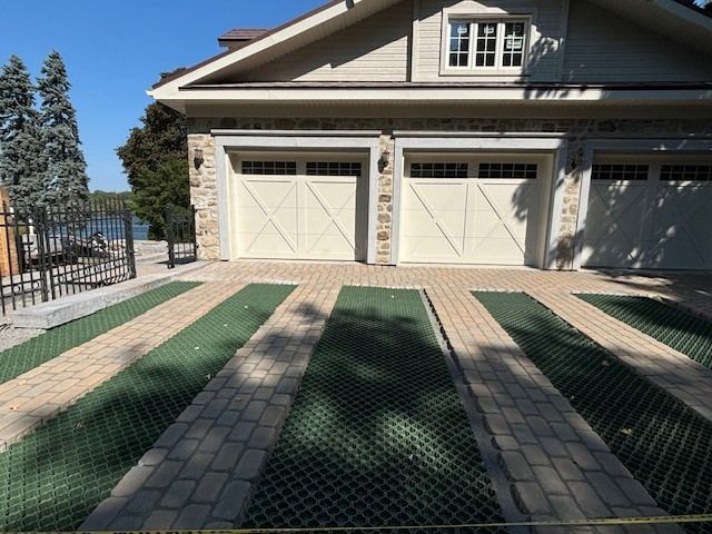 Une maison avec deux portes de garage et une allée verte