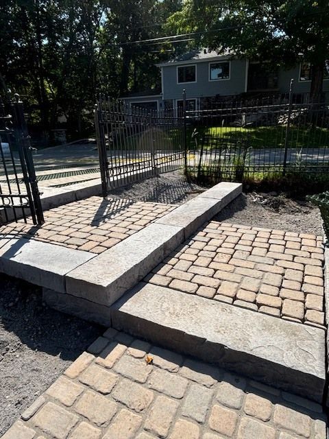 Une allée en briques avec une clôture et une maison en arrière-plan