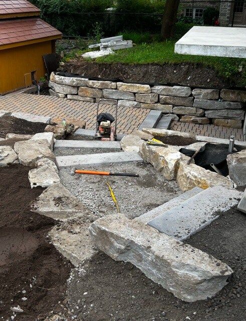 Un homme travaille sur un escalier en pierre dans une cour arrière.