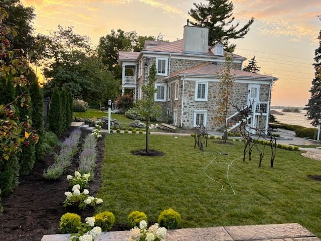 Une grande maison en pierre avec une pelouse verte luxuriante devant elle.