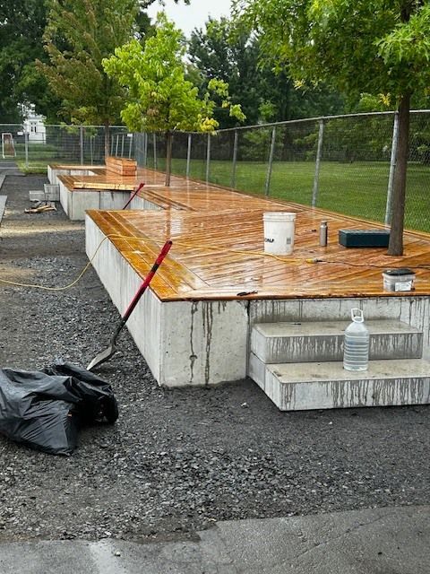Une bouteille de désinfectant pour les mains est posée sur le sol à côté d'une terrasse en bois