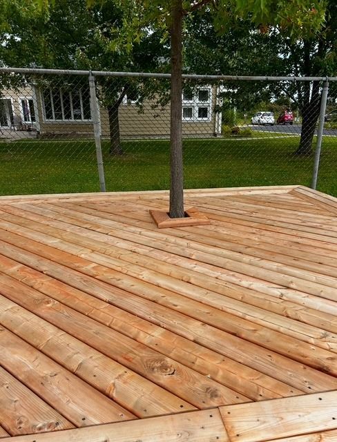 Une terrasse en bois avec un arbre au milieu