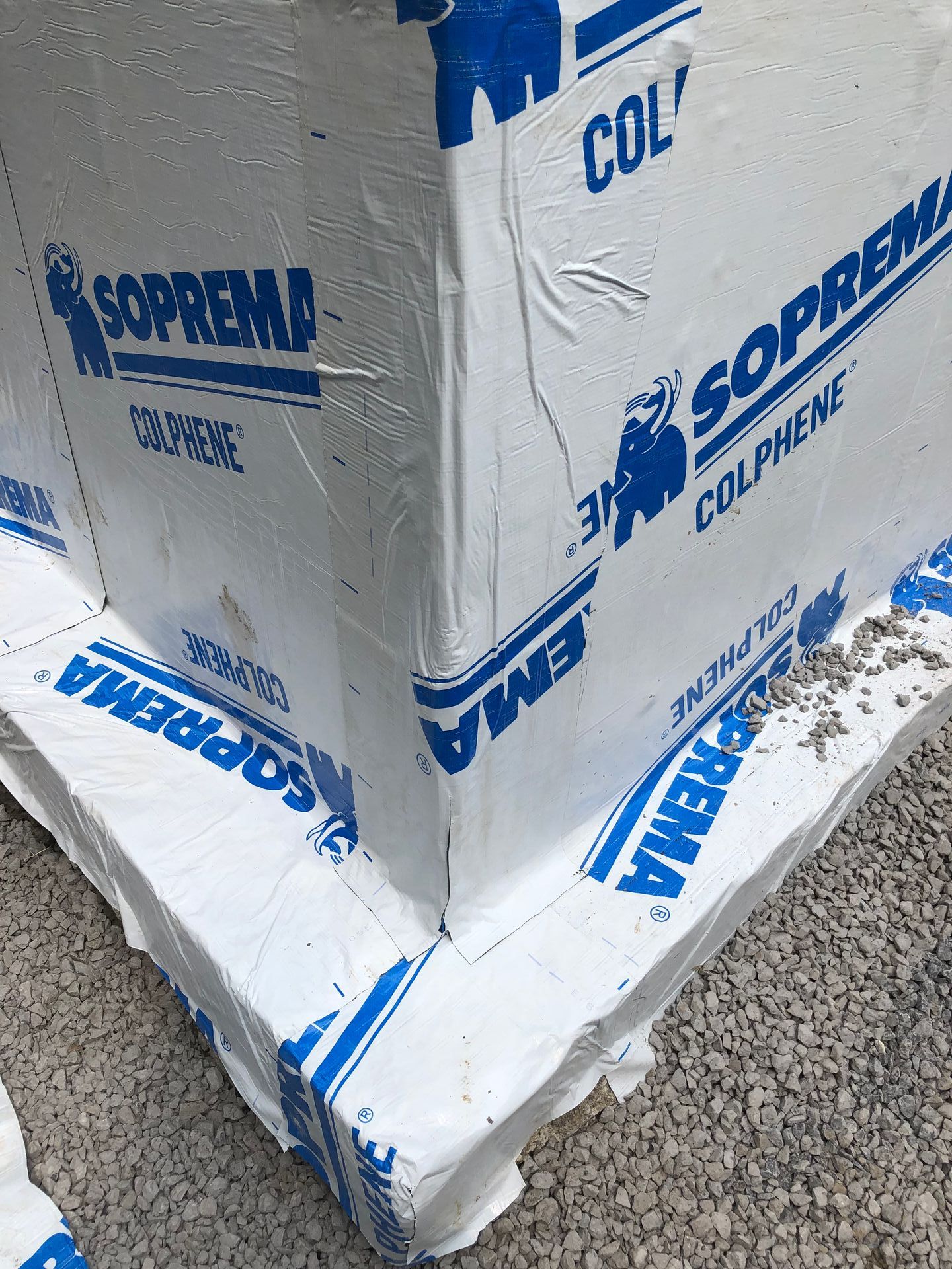 Une boîte blanche avec une écriture bleue dessus est posée sur un tas de gravier.