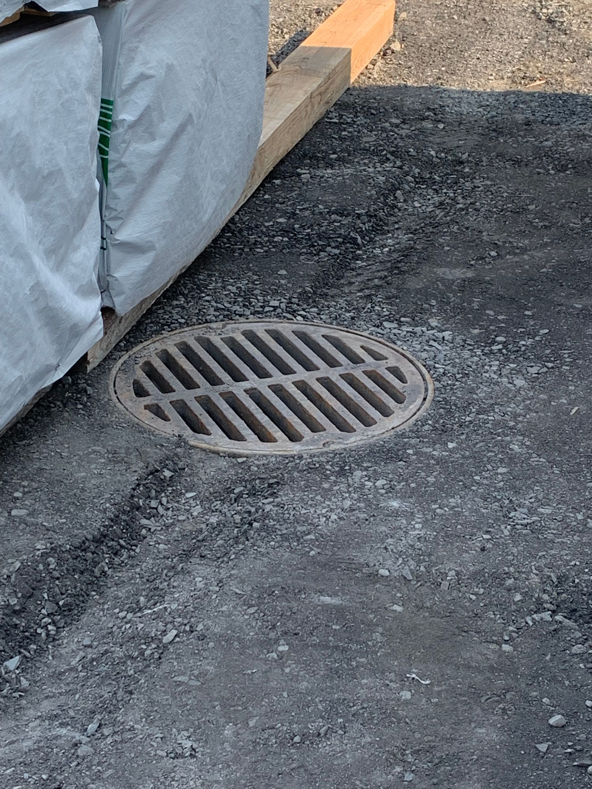 Un couvercle de trou d'homme est posé sur le sol à côté d'une palette en bois.