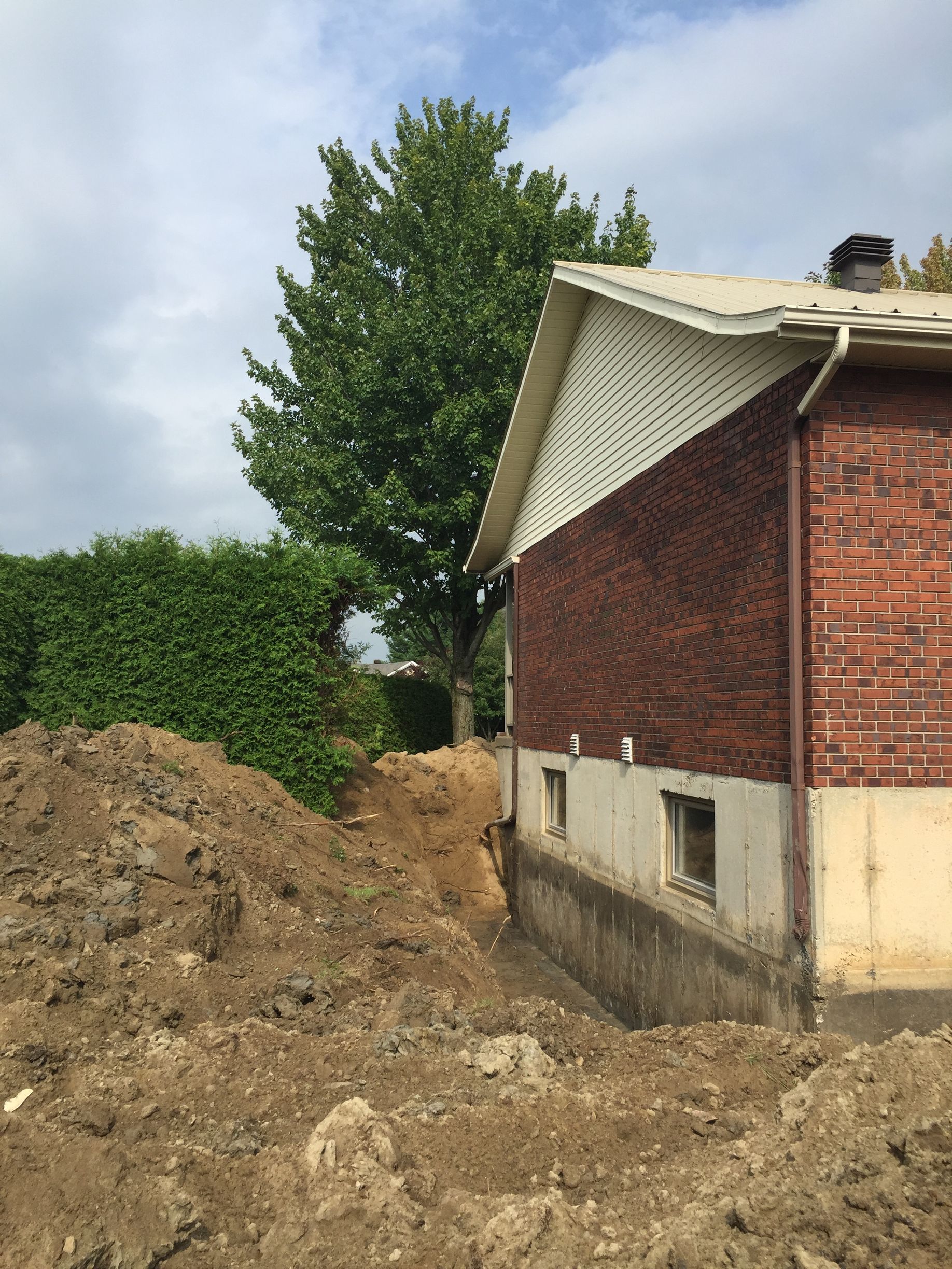 Une maison en briques avec un gros tas de terre devant elle
