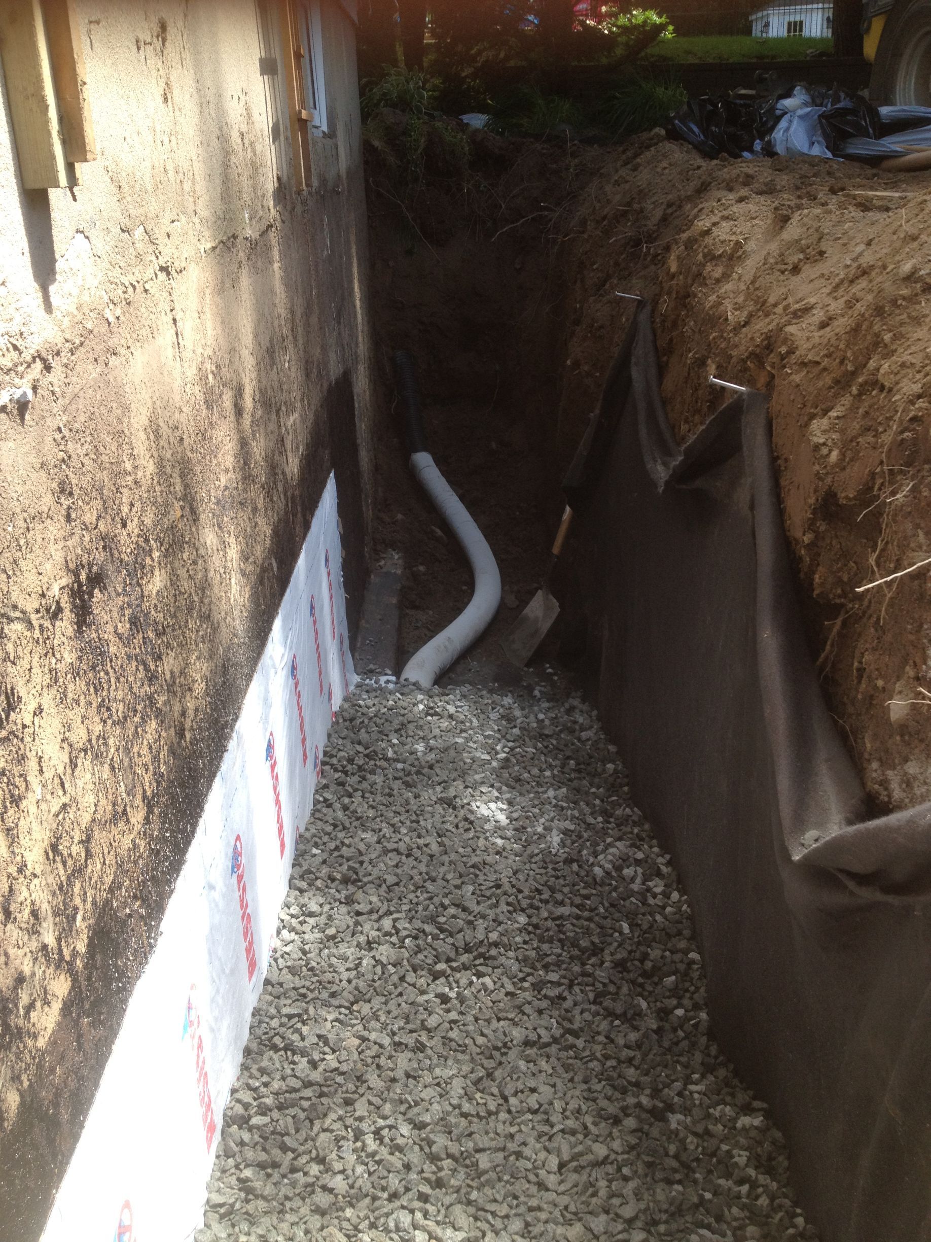 Un système de drainage est en cours d'installation sur le côté d'une maison.
