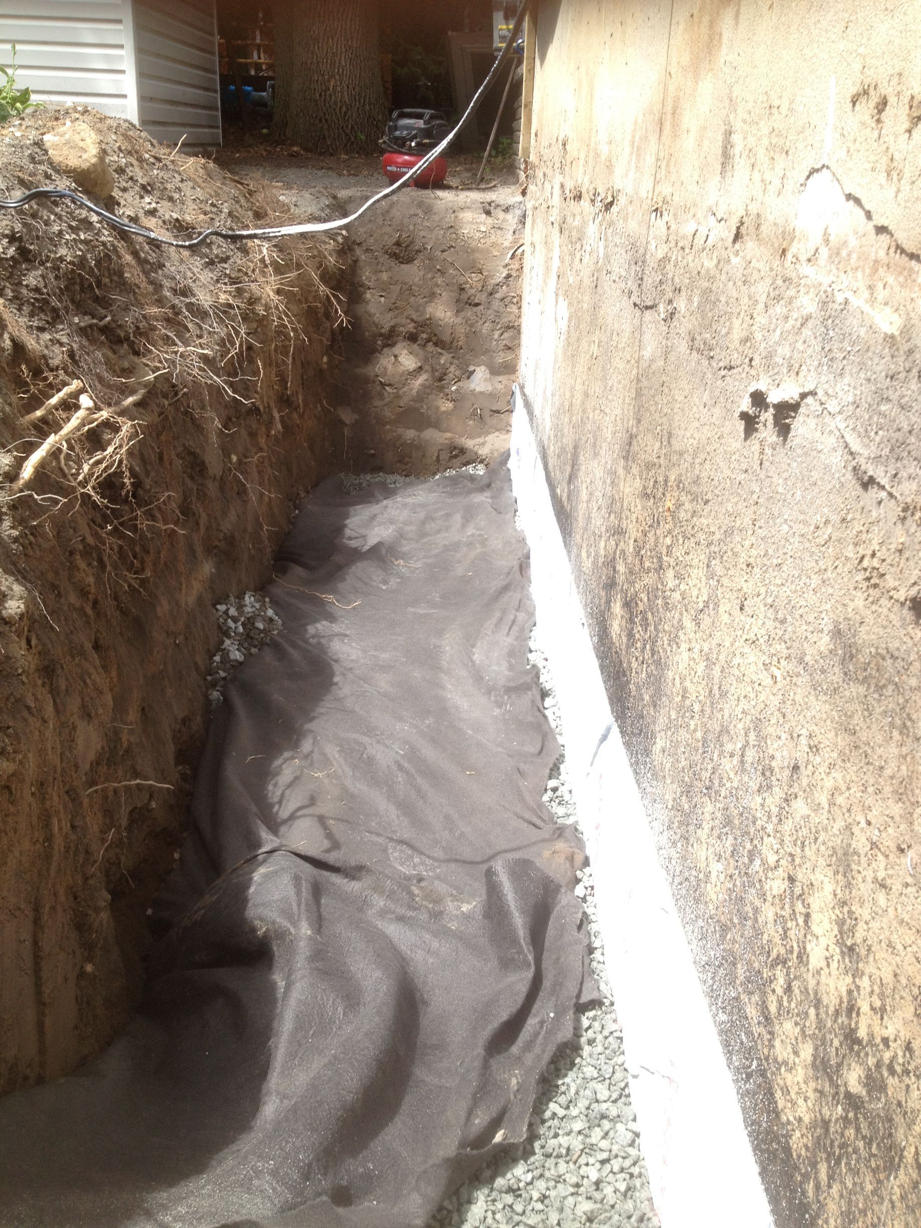 Un système de drainage est en cours d'installation sur le côté d'une maison.