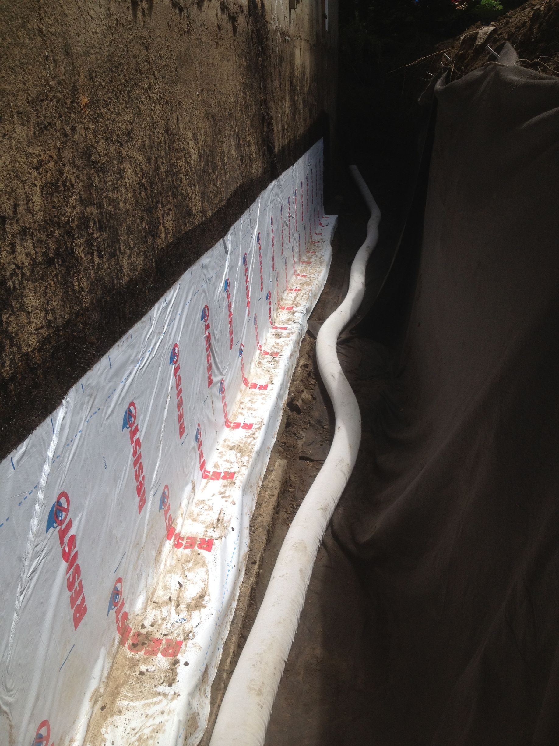 Un système de drainage est en cours d'installation sur le côté d'un bâtiment.