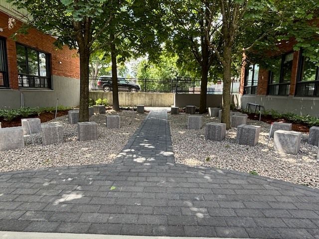 Une allée en briques entourée d'arbres et de rochers menant à un bâtiment.