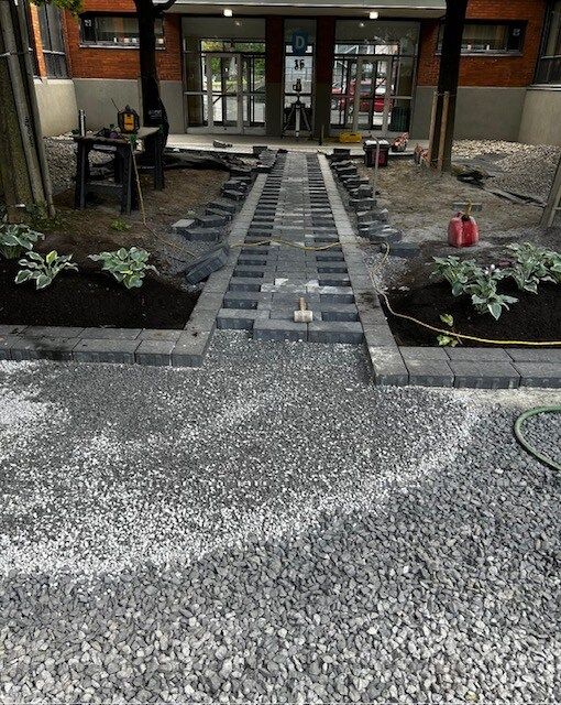 Un chemin de gravier est en cours de construction devant un bâtiment.