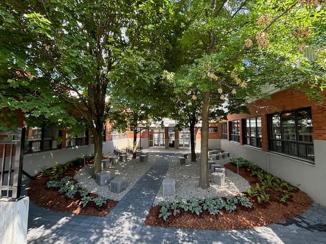 Une cour avec des arbres et des bancs devant un immeuble