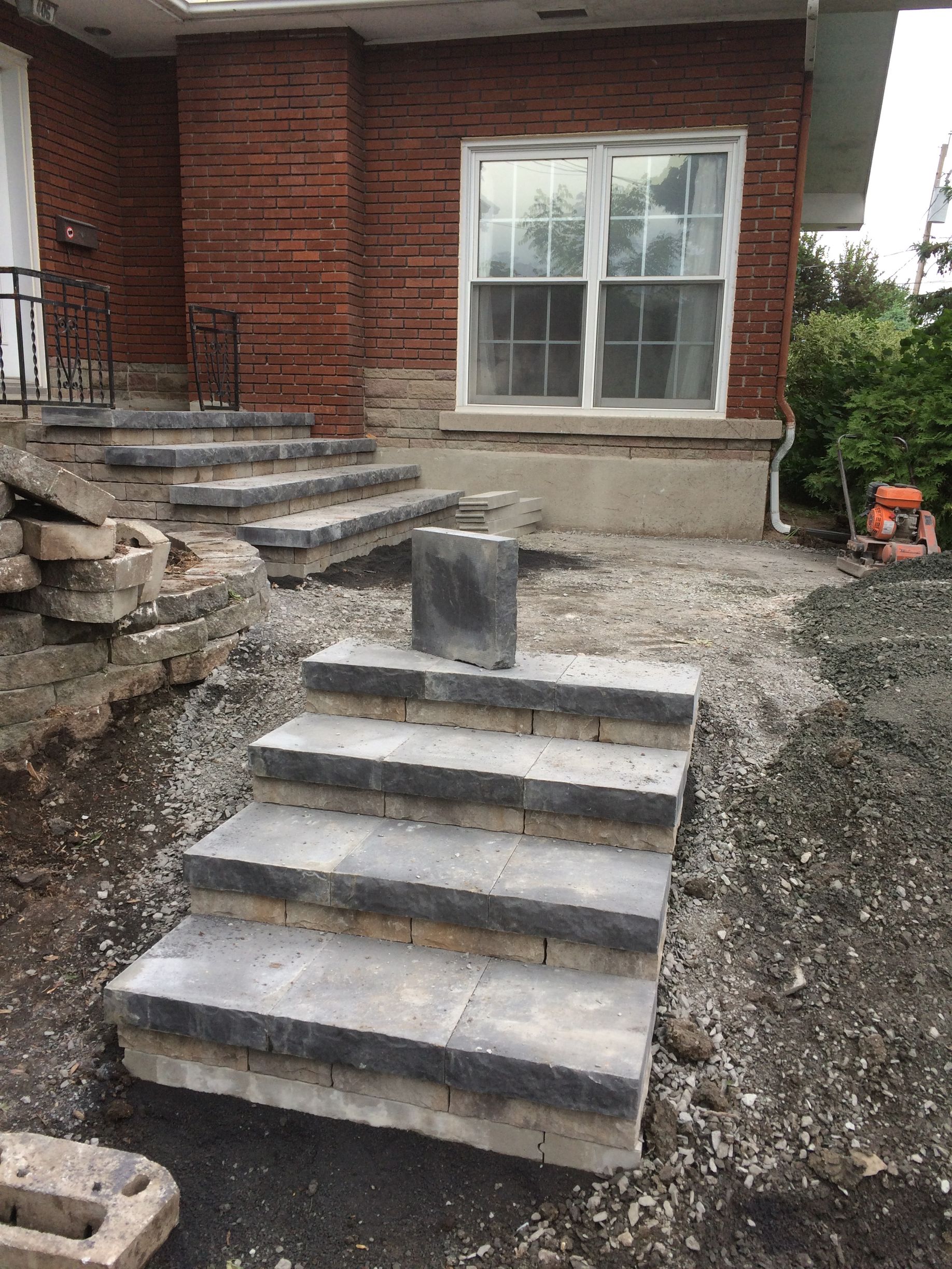 Un ensemble d'escaliers est en cours de construction devant une maison en briques.