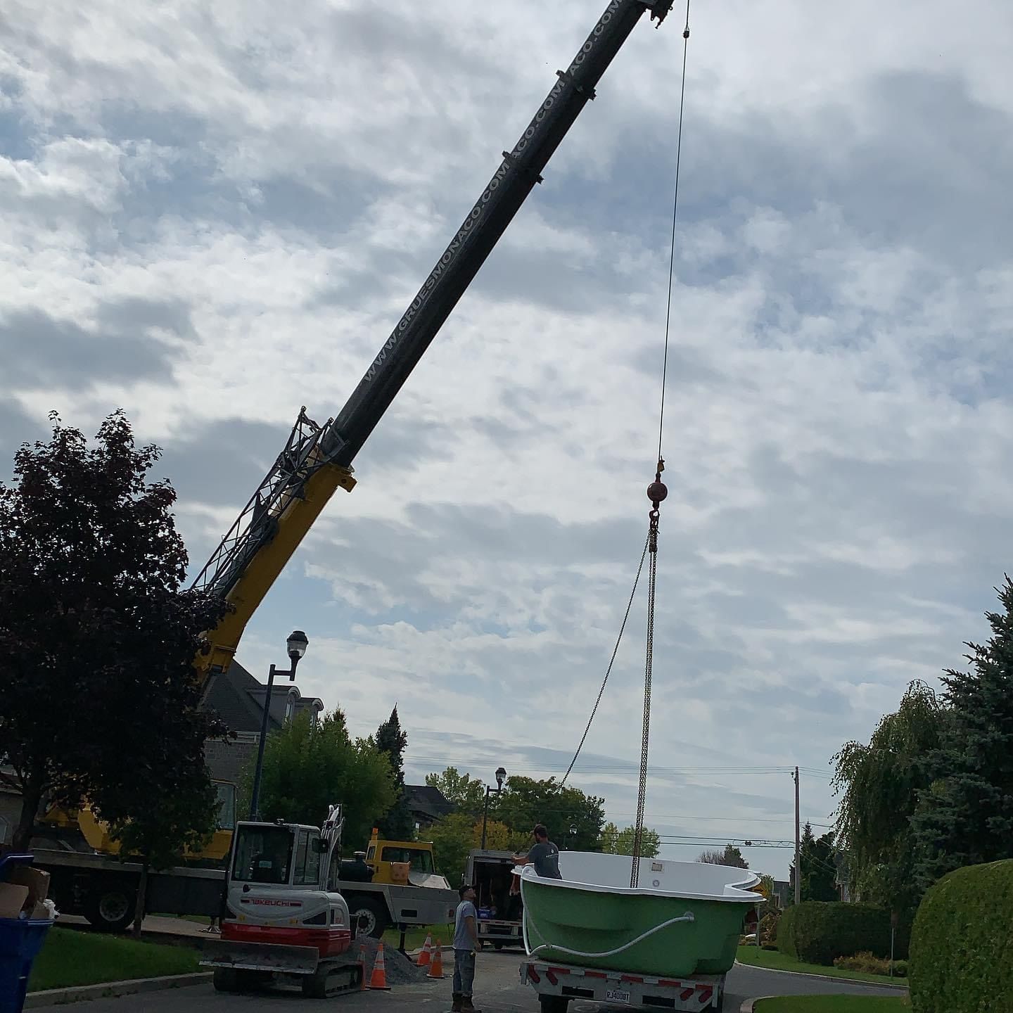 Une grue soulève un bac vert dans les airs