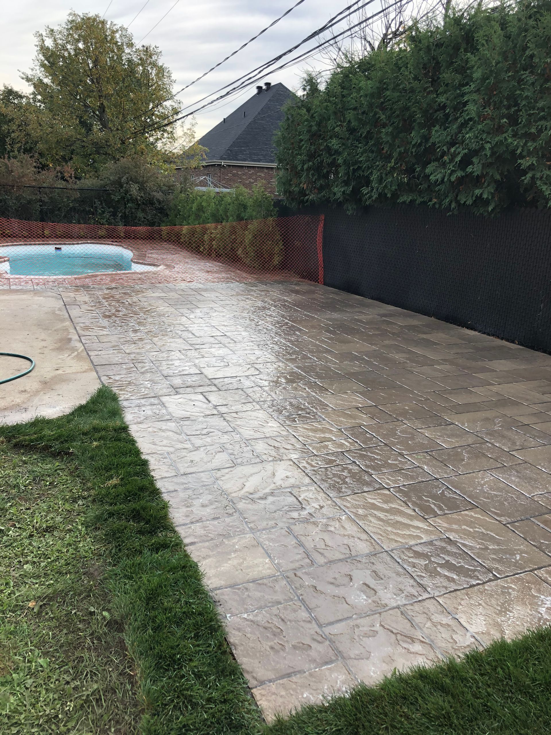 Une allée en béton menant à une piscine dans une cour arrière.
