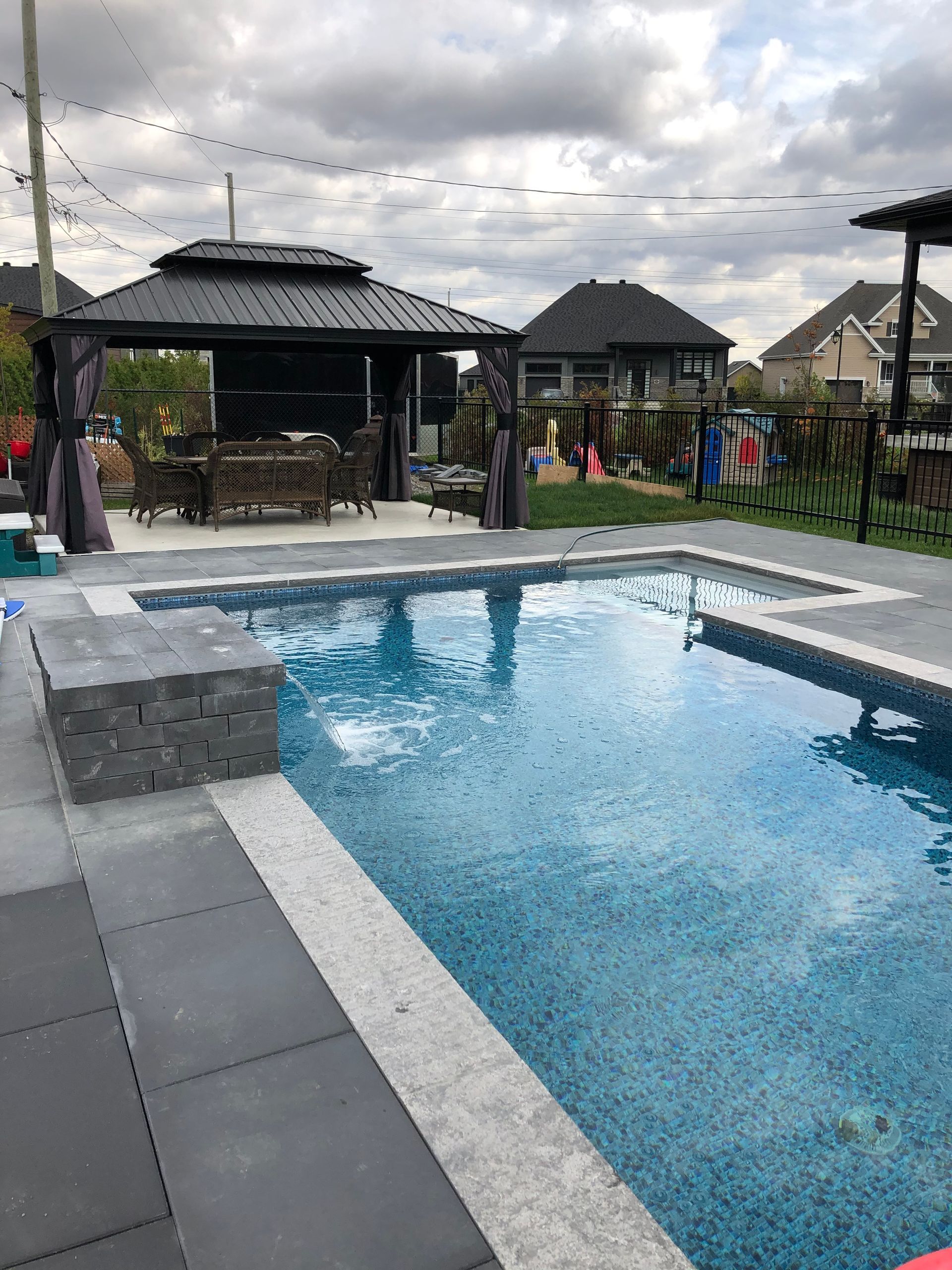Une grande piscine dans une cour arrière avec un belvédère en arrière-plan.