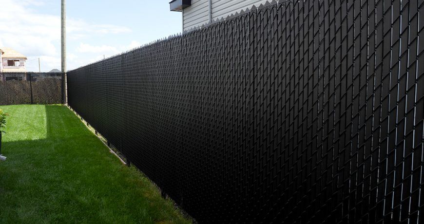 Une clôture noire entoure une cour verte luxuriante.