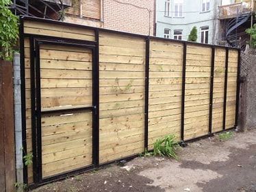 Une clôture en bois avec une porte dans l'arrière-cour d'un bâtiment.