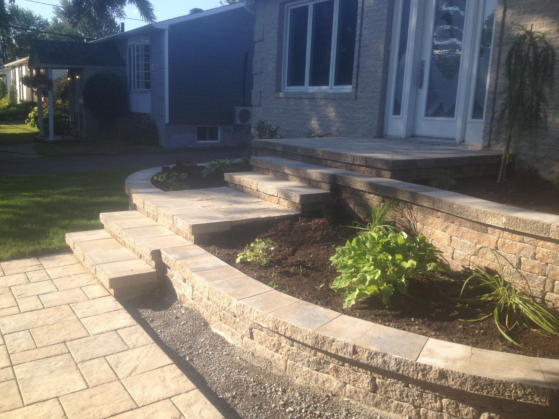 Une allée en briques menant à une maison avec une jardinière devant.