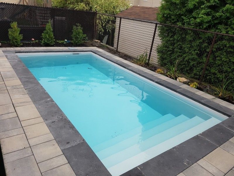 Une piscine avec des escaliers et une clôture en arrière-plan