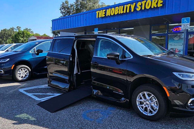 Black wheelchair-accessible van with open side door and ramp in front of 