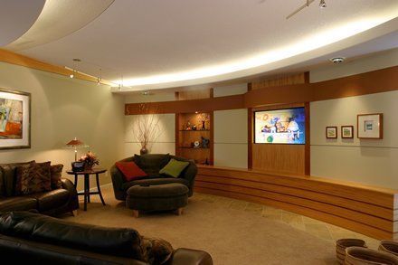 A living room with a couch , chair , ottoman and television.