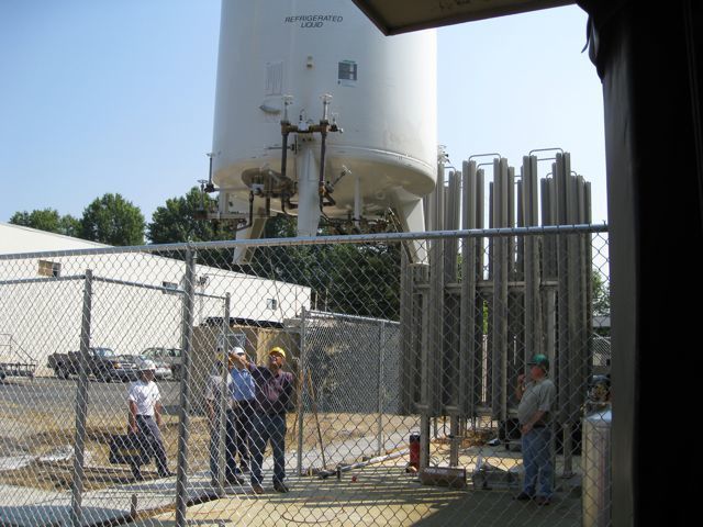 A chain link fence surrounds a large white tank