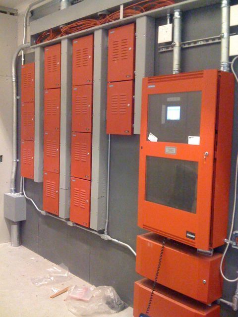 A row of orange lockers are lined up on a wall next to an orange box