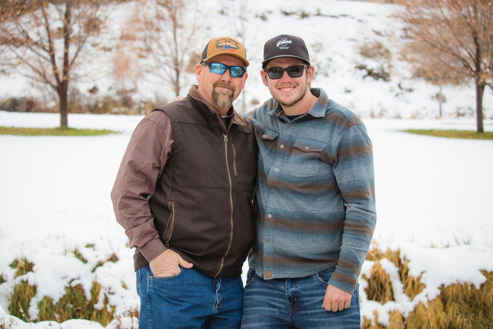 A father and son are posing for a picture in the snow.