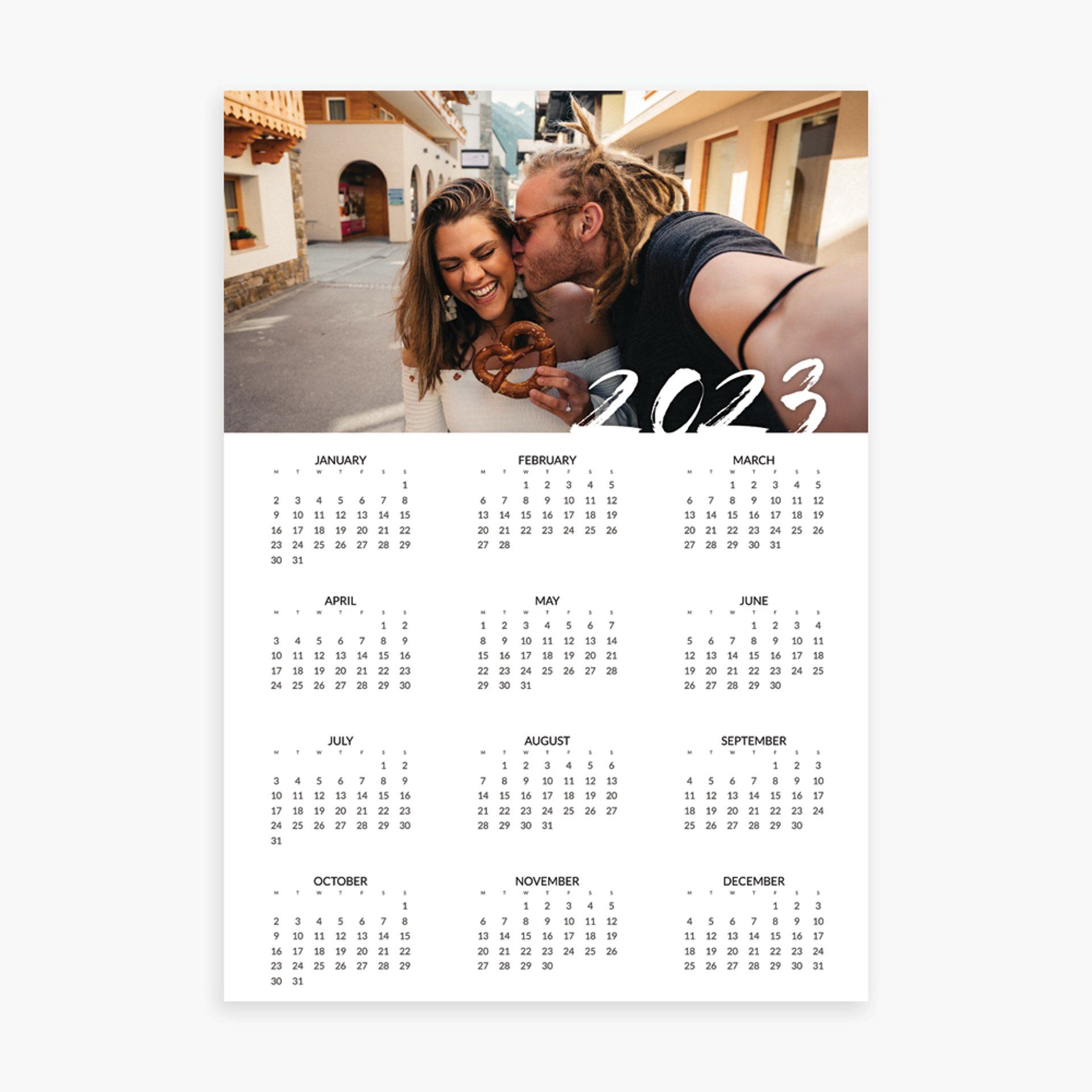A calendar with a picture of a man kissing a woman on the cheek.