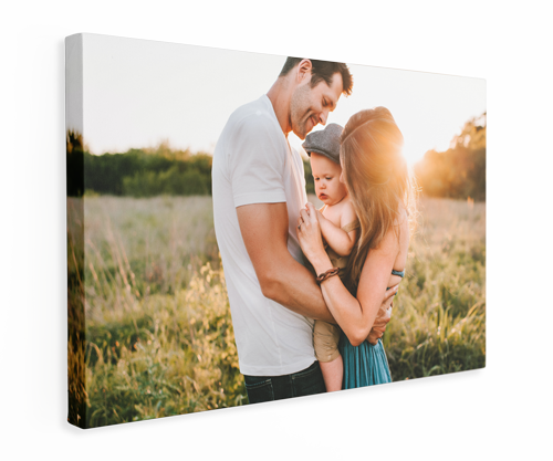 A man and woman are holding a baby in a field.