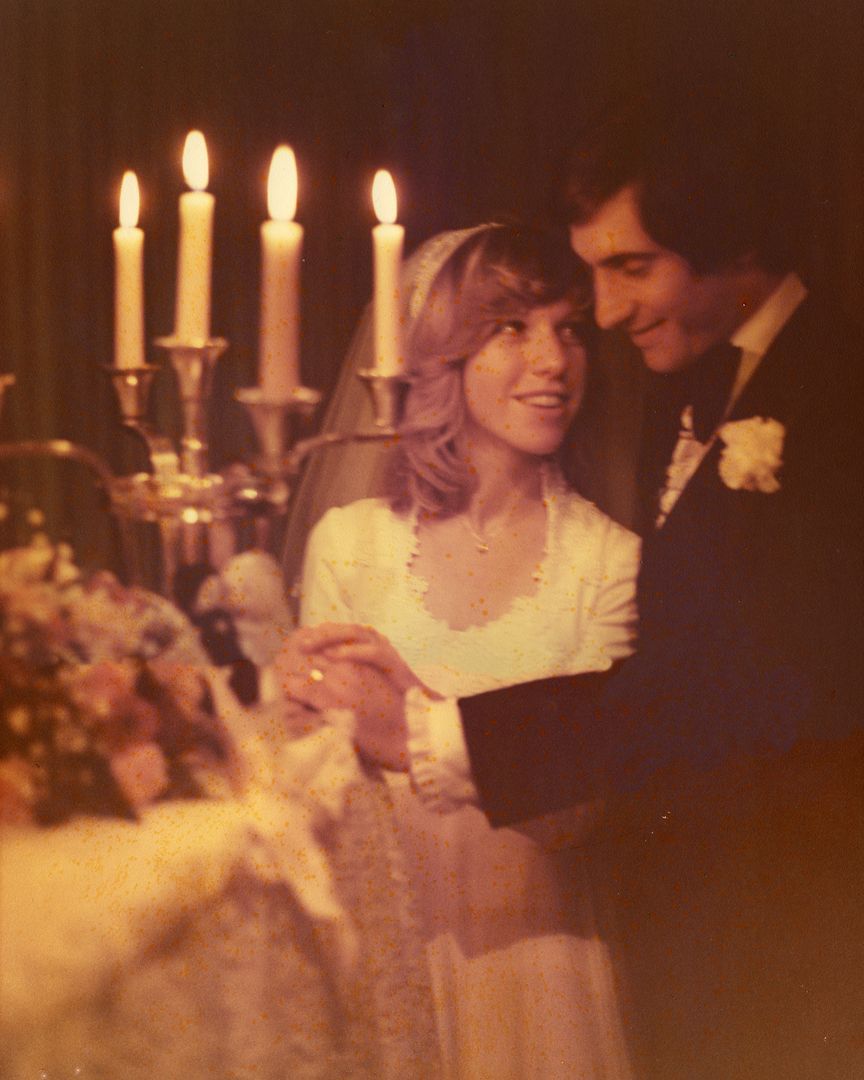 A bride and groom holding hands in front of candles