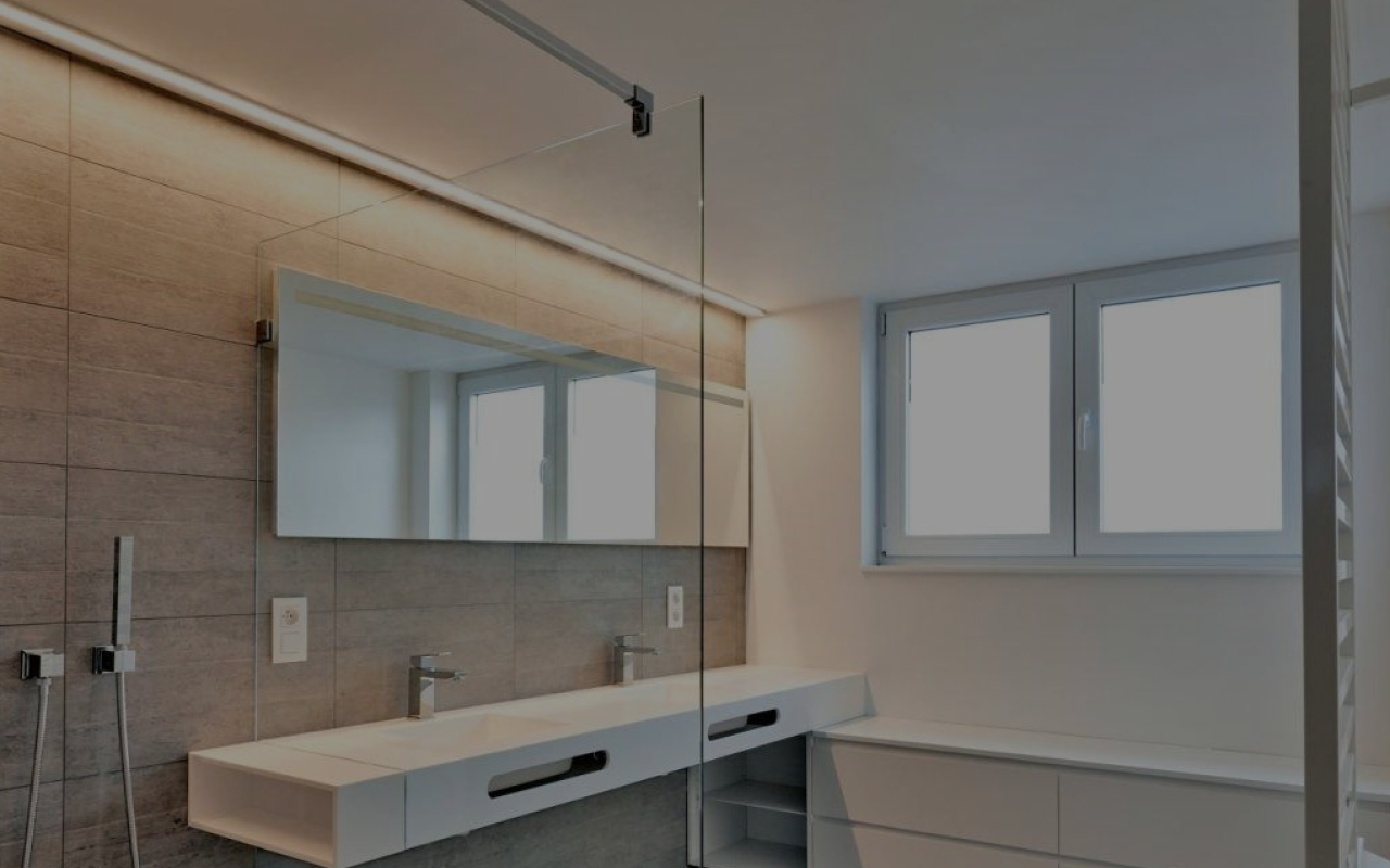 A bathroom with two sinks , a mirror and a walk in shower.