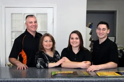 A group of people are posing for a picture in front of a counter - Select Automotive