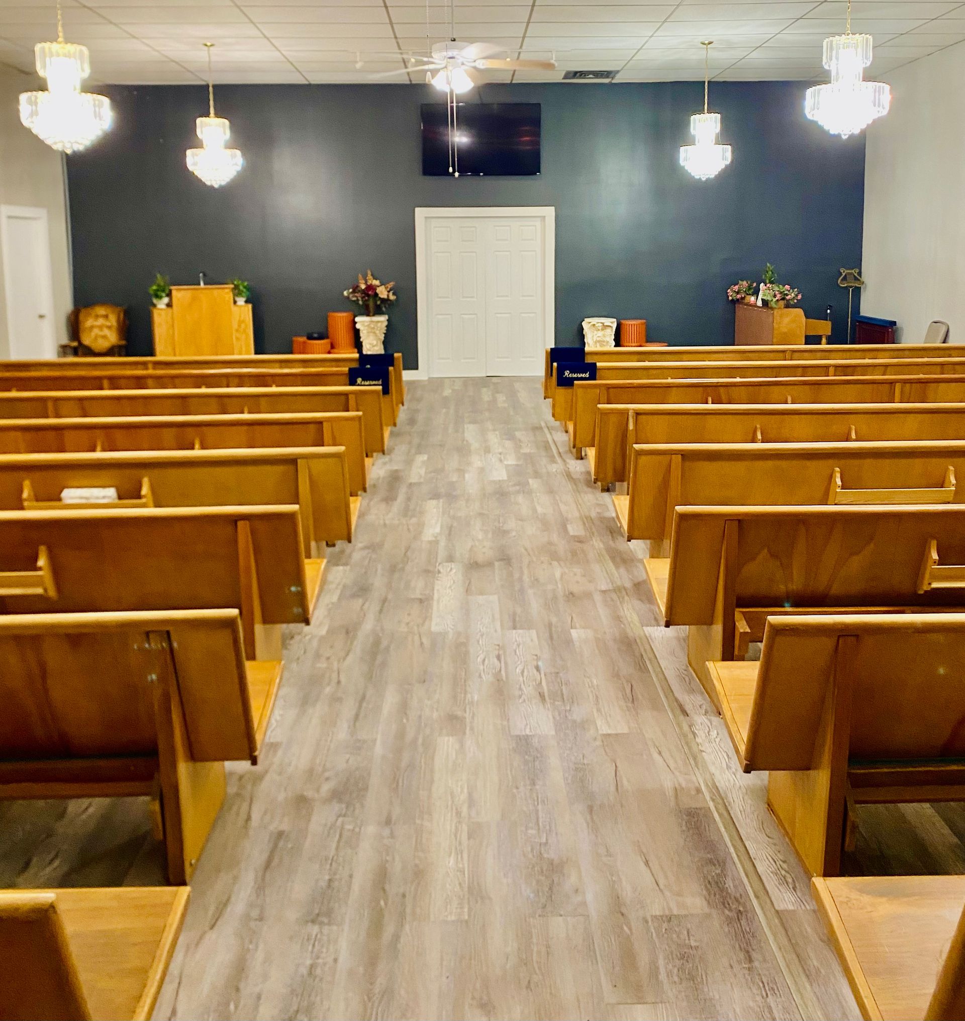 rows of wooden benches in a church with red and white curtains