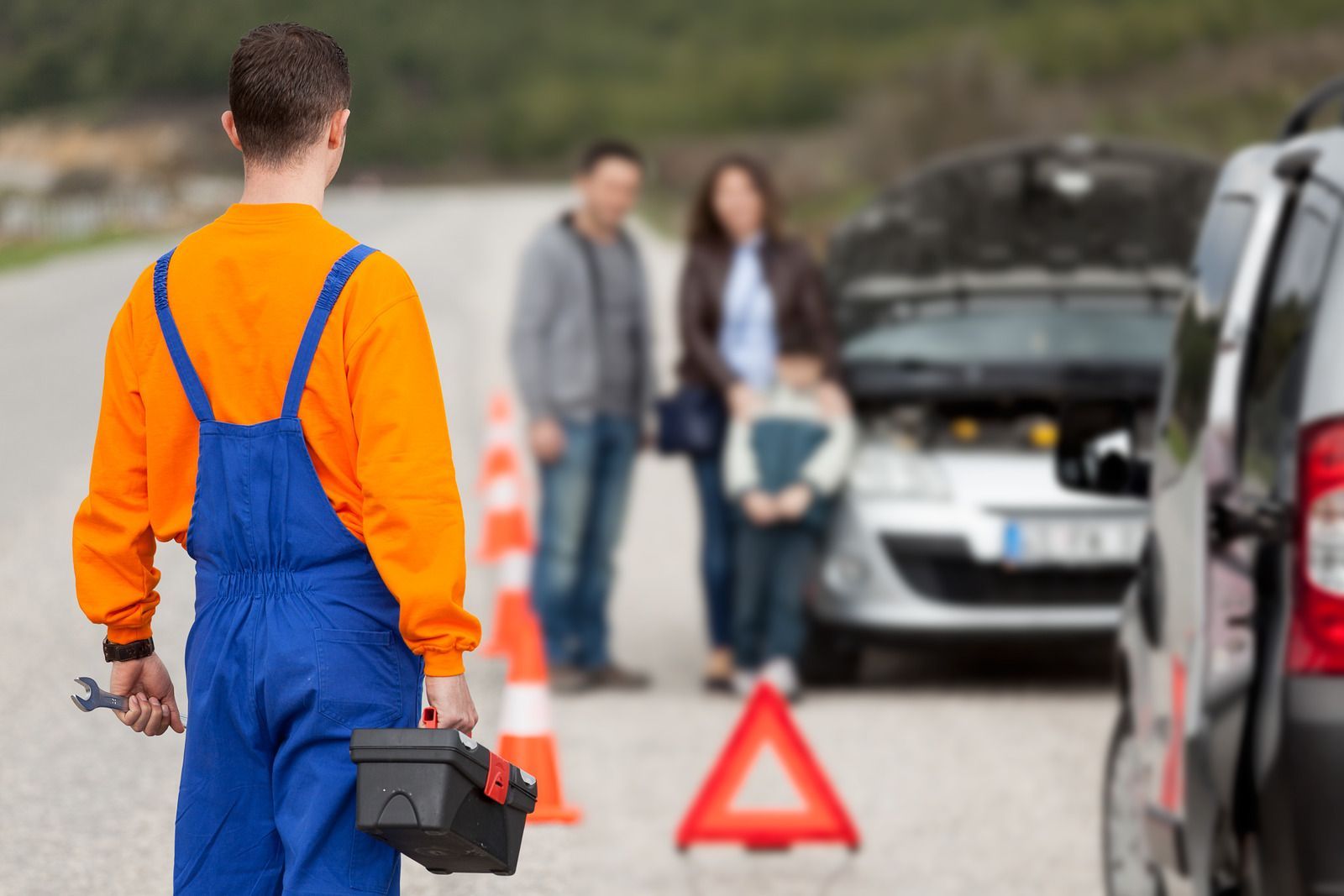 A man is standing in front of a broken down car.